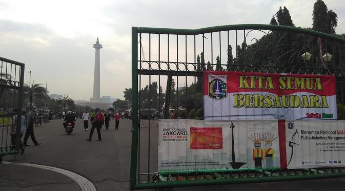 Spanduk bertuliskan 'Kita Semua Bersaudara' terpampang di pagar pintu masuk Monas, Jakarta Pusat, Jumat (11/4/2016). (Hanz Jimenez Salim/Liputan6.com)