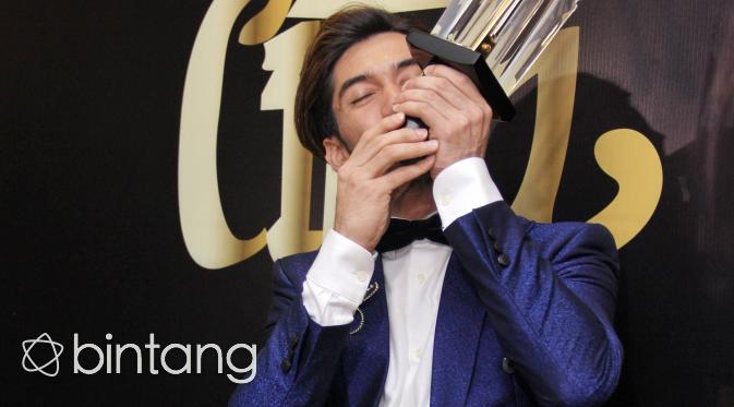 Ekspresi Reza Rahadian sambil mencium piala yang baru saja diraihnya. Perannya sebagai Bossman di film My Stupid Boss, ia terpilih menjadi Pemeran Utama Pria Terbaik. (Adrian Putra/Bintang.com)