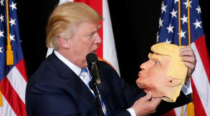 Capres dari Partai Republik Donald Trump melihat topeng wajah dirinya saat berkampanye di Sarasota, Florida, AS (7/11). Pilpres AS 2016 akan diadakan pada 8 November 2016 dan menjadi pilpres empat tahunan ke-58.  (REUTERS/Carlo Allegri) 