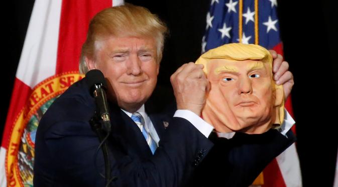 Ekspresi Donald Trump saat menunjukan topeng wajah dirinya ke awak media saat berkampanye di Sarasota, Florida, AS (7/11). Pilpres AS 2016 akan diadakan pada 8 November 2016 dan menjadi pilpres empat tahunan ke-58.  (REUTERS/Carlo Allegri) 