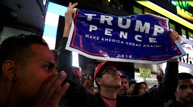 Seorang pendukung capres dari Partai Republik Donald Trump membentangkan spanduk saat perhitungan suara Pilpres AS 2016 di Manhattan, New York, AS, (8/11). (REUTERS/Bria Webb)