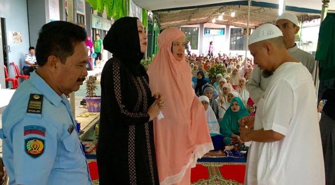 Angelina Sondakh (hijab hitam) berdiri di hadapan penghuni rutan pondok bambu lainnya bersama Ustaz Arifin Ilham.