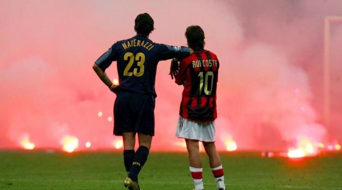 Marco Materazzi dan Rui Costa menyaksikan aksi pelemparan suar ke lapangan yang dilakukan Ultras Inter yang menghuni curva Nord Stadion Giuseppe Meazza pada leg kedua perempat final Liga Champions 2004-2005. 