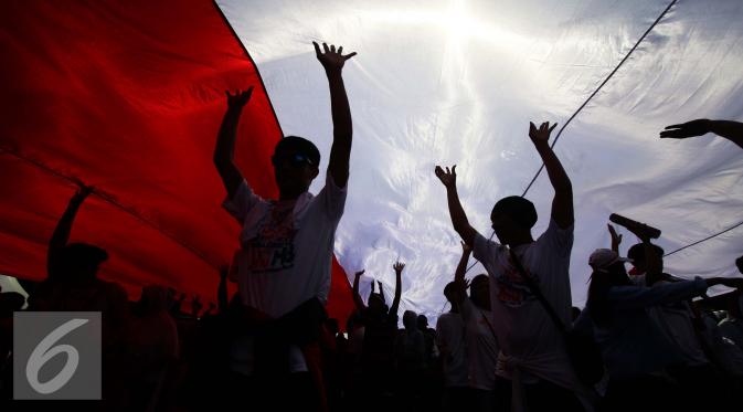 Sejumlah peserta membentangkan bendera merah putih saat aksi Parade Bhineka Tunggal Ika di kawasan Patung Kuda, Jalan MH Thamrin, Jakarta Pusat, Sabtu (19/11). Parade tersebut bertujuan untuk mempererat persatuan bangsa. (Liputan6.com/Gempur M. Surya)