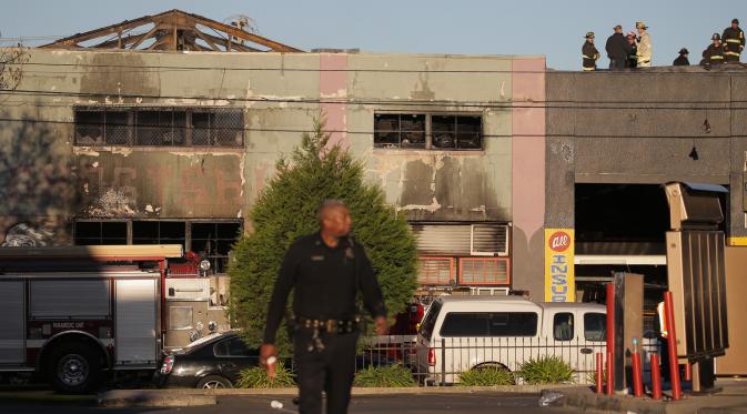 Polisi dan petugas pemadam masih berada di sebuah kelab malam yang mengalami kebakaran di Oakland, California, Sabtu (3/12). Pihak berwenang memperkirakan korban tewas bisa meningkat mencapai 40. (Elijah Nouvelage/GETTY IMAGES NORTH AMERICA/AFP)
