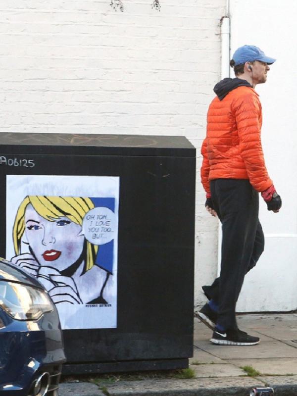 Tom Hiddleston melewati mural Taylor Swift yang berisikan pesan untuknya di sebuah jalan di London, Minggu (4/11/2016)