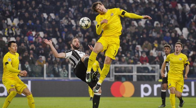 Penyerang Juventus, Gonzalo Higuain, duel udara dengan pemain Dinamo Zagreb, Mario Situm. Pada laga ini Juve melepaskan tujuh kali tembakan ke arah gawang, sementara Dinamo Zagreb hanya dua kali. (Reuters/Giorgio Perottino)