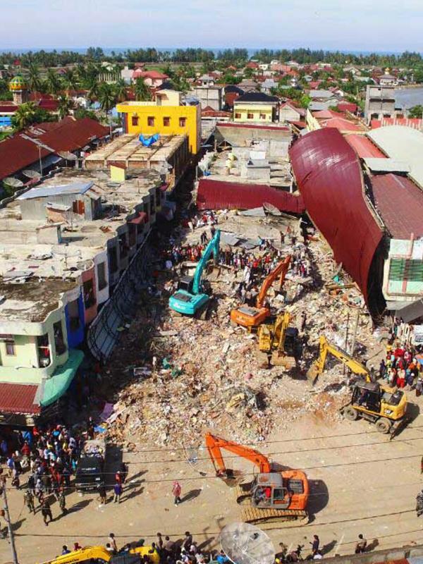 Pemandangan dari atas saat sejumlah eskavator dikerahkan untuk mengangkat puing-puing di Pasar Meureudu, Pidie Jaya, Aceh yang runtuh akibat gempa, Kamis (8/12). Dikabarkan korban meninggal sudah mencapai 102 orang. (Liputan6.com/Angga Yuniar)