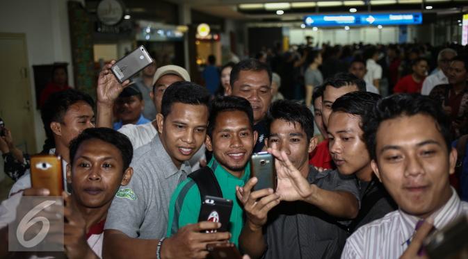 Gelandang serang tim nasional Sepak Bola Indonesia, Andik Vermansyah berfoto bersama masyarakat saat tiba di Bandara Soekarno Hatta, Jakarta, Kamis (8/12). (Liputan6.com/Faizal Fanani)