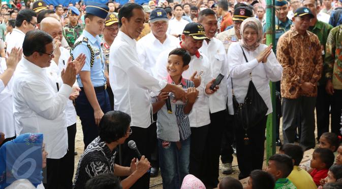 Presiden Jokowi memberikan hadiah kepada seorang anak yang menjawab pertanyaan saat meninjau tenda pengungsian korban gempa Aceh di Pidie Jaya, Jumat (9/12). Dalam kunjungan itu, Jokowi membagikan buku tulis untuk anak-anak. (Liputan6.com/Angga Yuniar)