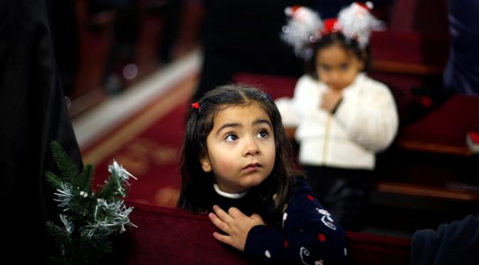 Seorang anak perempuan menghadiri misa pra natal di Gereja Der Latin di Gaza City, 18 December (REUTERS/Suhaib Salem)
