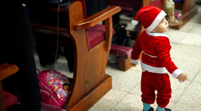Bocah Palestina dengan kostum Sinterklas menghadiri misa pra-natal di Gereja Der Latin, di Gaza City, 18 Desember 2016, (REUTERS/Suhaib Salem)