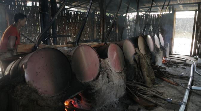 Perajin tengah memanaskan saringan fermentasi tetes tebu dalam tungku api (Liputan6.com/Mochamad Khadafi) 
