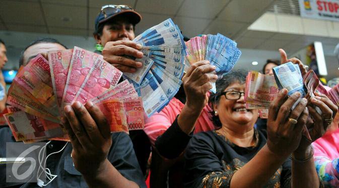 Masyarakat menunjukan mata uang rupiah lama yang akan ditukarkan dengan pecahan mata uang yang baru di Blok M, Jakarta, Senin (19/12). (Liputan6.com/Angga Yuniar)