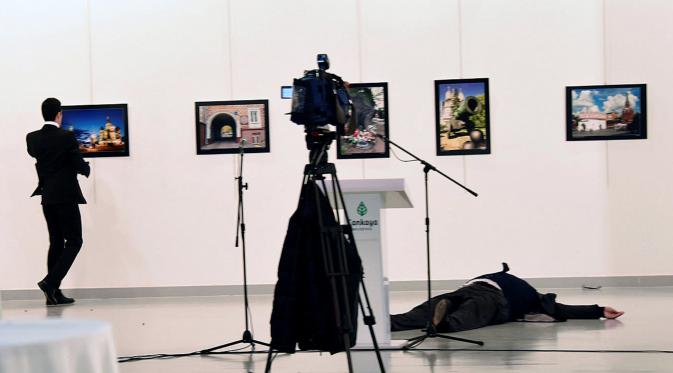 Dubes Rusia untuk Turki, Andrei Karlov tergeletak di lantai usai ditembak dari belakang oleh mantan anggota kepolisian (kiri) di galeri seni di Ankara, Senin (19/12). Dubes Rusia ditembak saat sedang menyampaikan sambutannya. (Depo Photos via REUTERS)