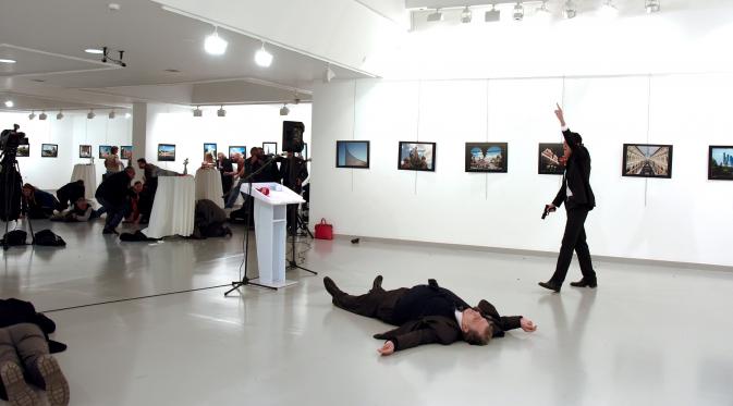 Dubes Rusia untuk Turki, Andrei Karlov tergeletak di lantai usai ditembak oleh seorang pria (kanan) di galeri seni di Ankara, Senin (19/12). Dubes Rusia ditembak dari belakang saat membuka pameran fotografi. (Depo Photos/Sozcu Newspaper via REUTERS)