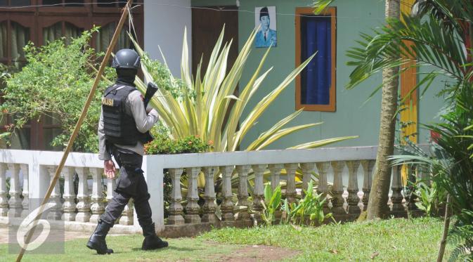 Petugas Kepolisian Brimob berjaga disekitar area rumah terduga teroris di Setu, Tangerang Selatan, Rabu (21/12). Setelah AN diinterogasi tim mendapatkan informasi bahwa bom akan diledakkan pada akhir tahun. (Liputan6.com/Helmi Affandi)