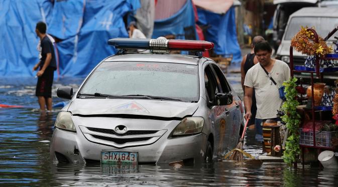 Sebuah mobil polisi terendam banjir yang disebabkan oleh hujan dari Topan Nock-Ten di kota Quezon, utara Manila, Filipina, (26/12). Topan super Nock-ten atau dikenal dengan Nina menerjang Filipina bertepatan saat Natal. (AP Photo / Aaron Favila)