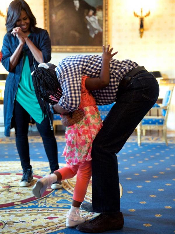 Michelle Obama tersenyum melihat Obama memeluk Caprina Harris pada 28 Maret 2016. (Foto: Pete Souza/DailyMail)