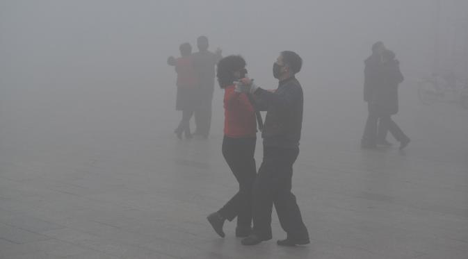 Warga mengenakan masker menari saat kabut tebal menyelimuti Fuyang, Provinsi Anhui, China, 3 Januari 2017. (China Daily/via Reuters)