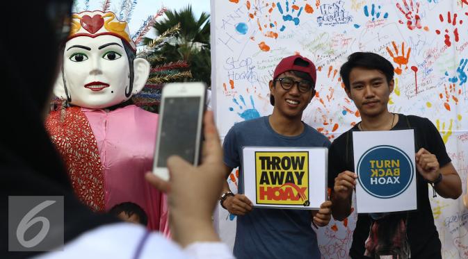 Warga berfoto menggunakan poster anti hoax saat kegiatan dekralarasi masyarakat anti hoax di kawasan Car Free Day, Jakarta, Minggu (8/1). Tujuan mereka adalah untuk menyikapi banyaknya konten palsu yang marak di media sosial. (Liputan6.com/Heman Zakharia)