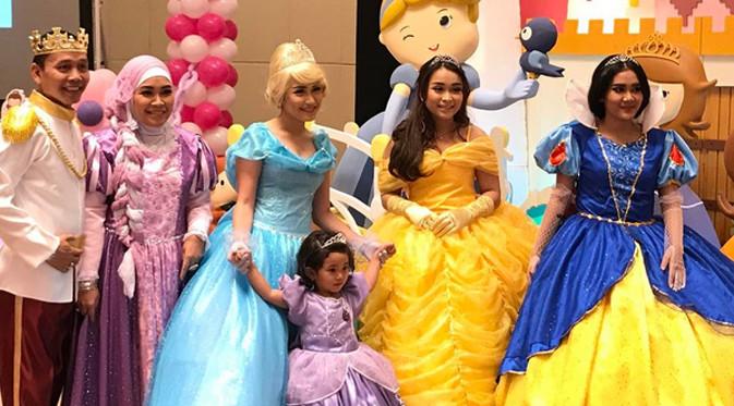 Bilqis mengenakan kostum Princess Sophia warna ungu. Dan Ayu mengenakan kostum Cinderella. Begitu juga dengan orangtua serta adiknya berdandan layaknya di negeri dongeng. (Instagram/bilqis3rdbirthday)