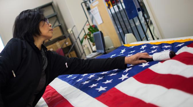 Seorang pekerja menyelesaikan pembuatan bendera Amerika Serikat yang akan digunakan untuk upacara pelantikan presiden baru Amerika Serikat Donald Trump, Alexandria Virginia, AS (10/1). (AFP/Andrew Caballero Reynolds)