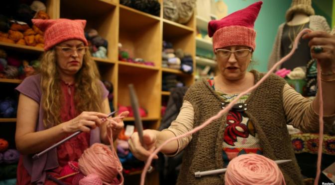 Dua perempuan yang terlibat pembentukan topi berbentuk vagina sebagai protes terhadap Donald Trump. (Reuters)