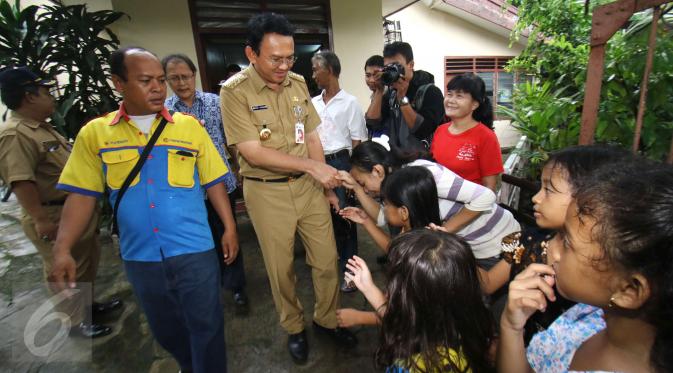 Ahok bersalaman dengan warga saat blusukan di Bukit Duri, Jakarta, Senin (20/2). Ahok juga menyempatkan diri untuk berinteraksi dan berdialog dengan warga terkait banjir yang sering melanda. (Liputan6.com/Helmi Afandi)