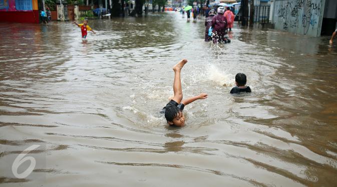 Seorang anak asyik bermain banjir yang merendam kawasan Benhil RT 03 RW 05, Jakarta Pusat, Selasa (21/1). Hujan deras yang mengguyur sejak Selasa dinihari mengakibatkan kawasan tersebut mengalami banjir. (Liputan6.com/Johan Tallo)