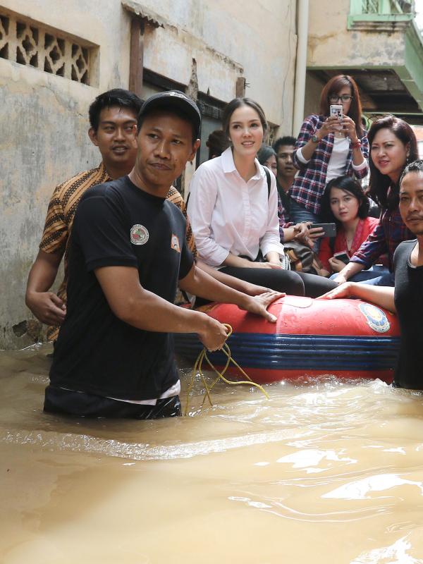 Aktris Cathy Sharon bersama istri wakil gubernur DKI Jakarta Heppy Farida djarot menaiki perahu karet meninjau lokasi banjir di jalan Bina Warga, Pancoran, Jakarta Selatan, Selasa (21/02). (Liputan6.com/Herman Zakharia)