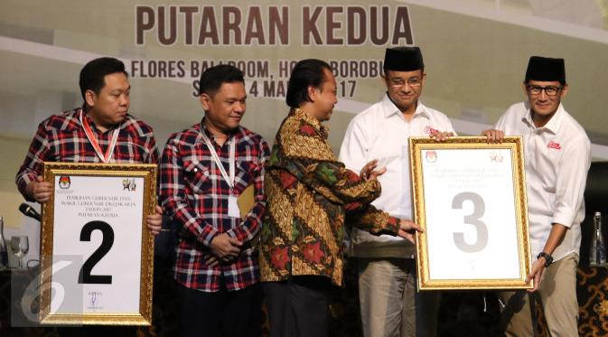 Pasangan cagub dan cawagub Anies Baswedan dan Sandiaga Uno menerima plakat yang diberikan oleh ketua KPU DKI Jakarta, Sumarno saat rapat pleno terbuka di Jakarta, Sabtu (4/3). (Liputan6.com/Angga Yuniar)