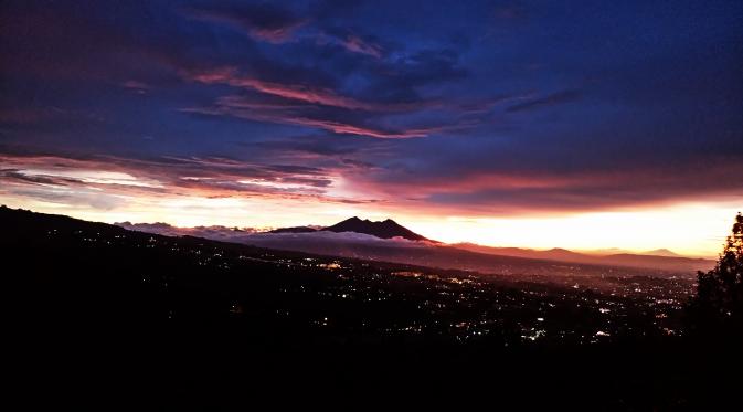 Senja berkabut berlatar kebun teh dan Gunung Salak dapat dinikmati dari kawasan wisata Puncak, Kabupaten Bogor, Jawa Barat. (Liputan6.com/Muhamad Nuramdani)