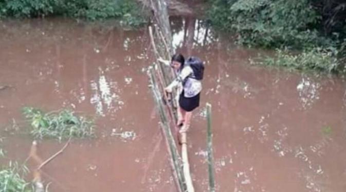 Bukan sedang uji adrenalin, tapi inilah jembatan angker yang harus dilalui oleh bu guru Lusia setiap harinya. (Foto: Facebook/Askiman Sintang)