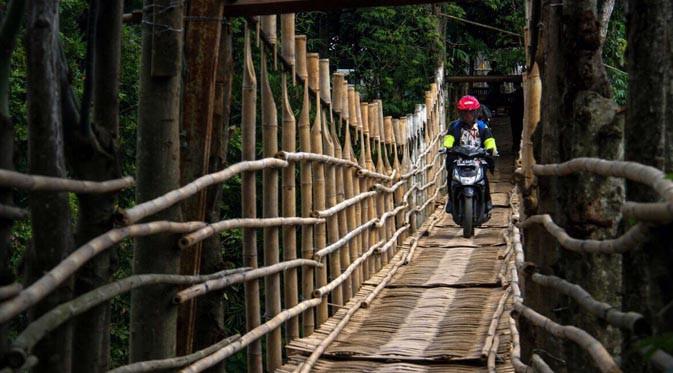 Warga melintasi jembatan bambu 