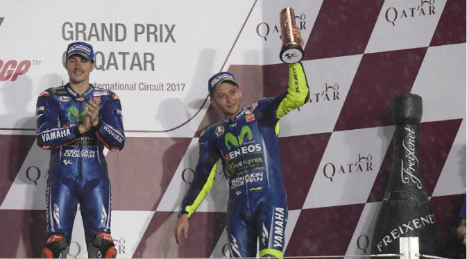 Pebalap Movistar Yamaha, Valentino Rossi (kanan), mengangkat trofi di podium setelah finis ketiga pada balapan MotoGP Qatar di Sirkuit Losail, Qatar, Minggu (26/3/2017). (Bola.com/Twitter/YamahaMotoGP)