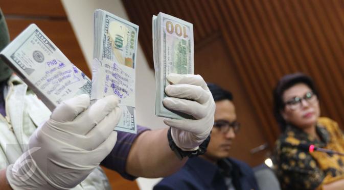 Petugas memperlihatkan uang yang berhasil disita dari pejabat PT PAL terkait dugaan suap pengadaan kapal ke Filipina, Jakarta, Jumat (31/3). KPK menyita 25 ribu dolar AS dan menahan 4 tersangka. (Liputan6.com/Helmi Afandi)