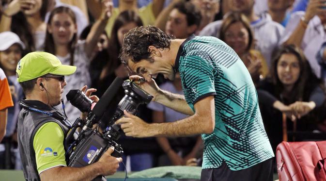 Roger Federer bercanda dengan kamera usai menumbangkan Nick Kyrgios  7-6(9), 6-7(9), 7-6(5). (AP Photo/Wilfredo Lee)