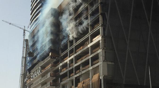 Petugas memadamkan api yang melanda sebuah gedung di sebelah Dubai Mall, Uni Emirat Arab, Minggu (2/4). Gedung yang terbakar diketahui sedang dikerjakan raksasa kontruksi Emaar. (AP Photo/ Jon Gambrell)