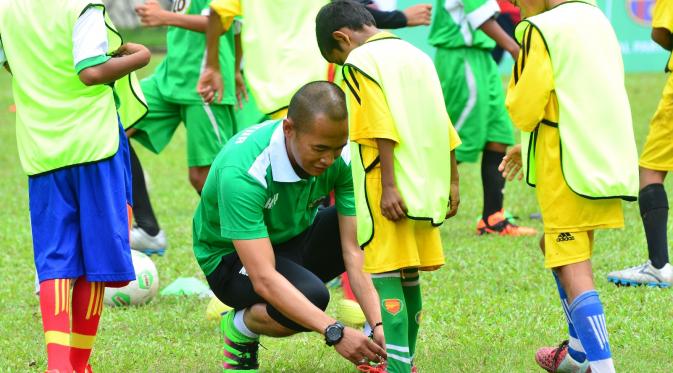 Kurniawan Dwi Yulianto saat membenarkan tali sepatu peserta coaching clinic di sela-sela Milo Football Championship Makassar (istimewa)