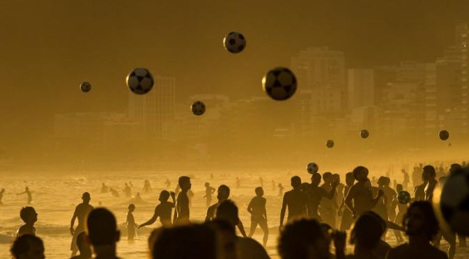 Orang-orang bermain sepak bola saat matahari terbenam di Pantai Ipanema di Rio de Janeiro, Brazil (AFP PHOTO/Yasuyoshi CHIBA).