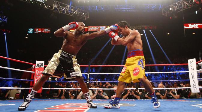 Floyd Mayweather Jr (kiri) berusaha memukul wajah Manny Pacquiao saat pertandingan kelas welterweight di MGM Grand Garden Arena, Las Vegas, Nevada, Minggu (3/5/2015). Floyd Mayweather berhasil manang angka atas Manny Pacquiao. (Mark J. Rebilas-USA TODAY)