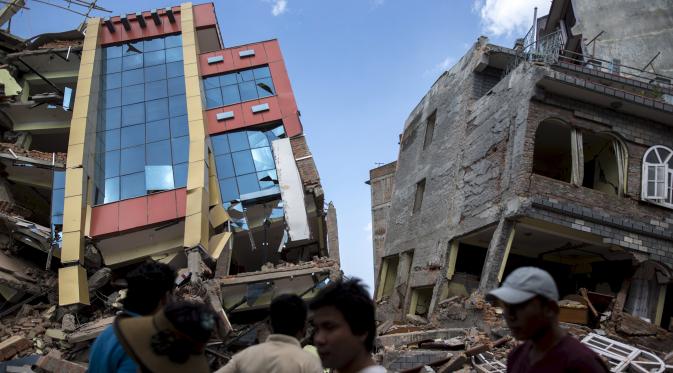 Warga berjalan melewati bangunan yang runtuh pascagempa susulan berkekuatan 7,3 SR melanda Kathmandu, Nepal, Selasa (12/5/2015). Sebelumnya, luka atas gempa dahsyat yang terjadi 25 April lalu di Nepal masih belum terobati. (REUTERS/Athit Perawongmetha)