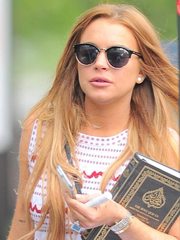 Lindsay Lohan tertangkap kamera sedang membawa Al Quran setelah menjalani kerja sosial pada hari pertamanya. (via dailymail.co.uk)