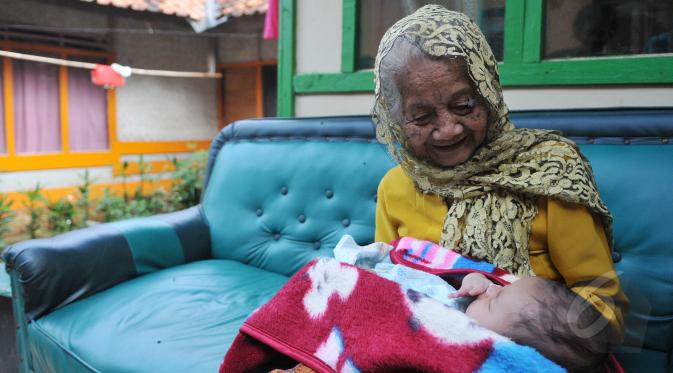 Nenek Anami terlihat menggendong seorang bayi di depan rumahnya di Purwakarta, Jabar, Minggu (17/5). Nenek yang diduga berusia 140 tahun ini akan mengikuti sayembara orang tertua di dunia dengan hadiah sekitar Rp13 miliar. (Liputan6.com/Herman Zakharia)