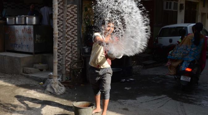 Pekerja India menyiram air di luar restoran | via: Getty Images