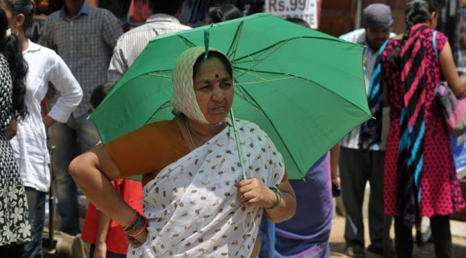 Wanita India ini pun menggunakan payung di hari yang panas | via: Getty Images