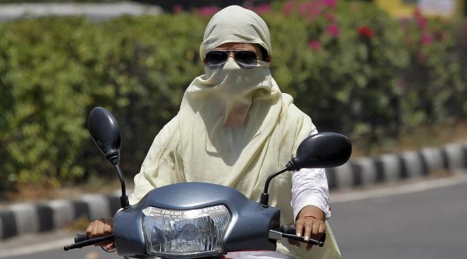 Seorang wanita mengendarai sepeda motor dengan wajah tertutup untuk melindungi diri dari sengatan matahari saat gelombang panas terjadi di India (28/5/2015). Dikabarkan 1.371 orang tewas karena suhu meningkat di atas 47 Celcius. (REUTERS/Ajay Verma)