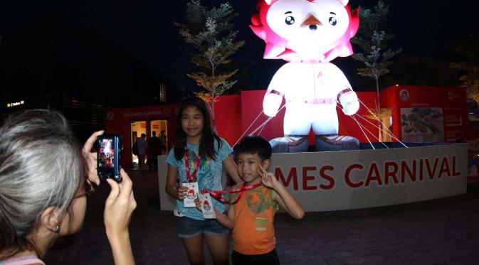Dua bocah berfoto di depan maskot SEA Games. (Bola.com/Arief Bagus)