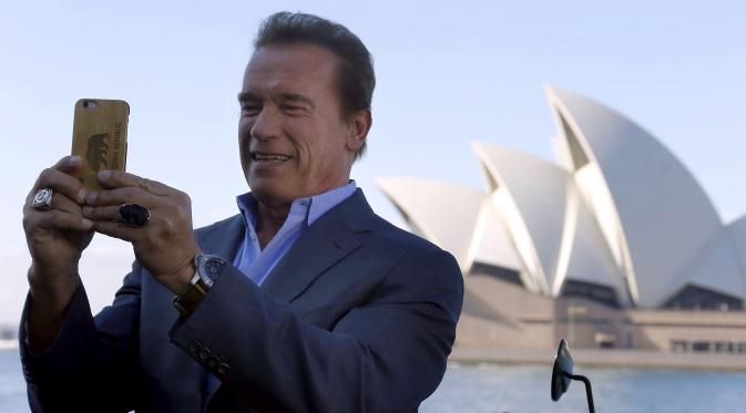 Mantan Gubernur California, Arnold Schwarzenegger melakukan selfie saat mempromosikan film terbarunya, `Terminator Genisys` di depan Sydney Opera House di Australia, Kamis (4/6/2015). Film tersebut disutradai oleh Alan Taylor. (REUTERS/David Gray)